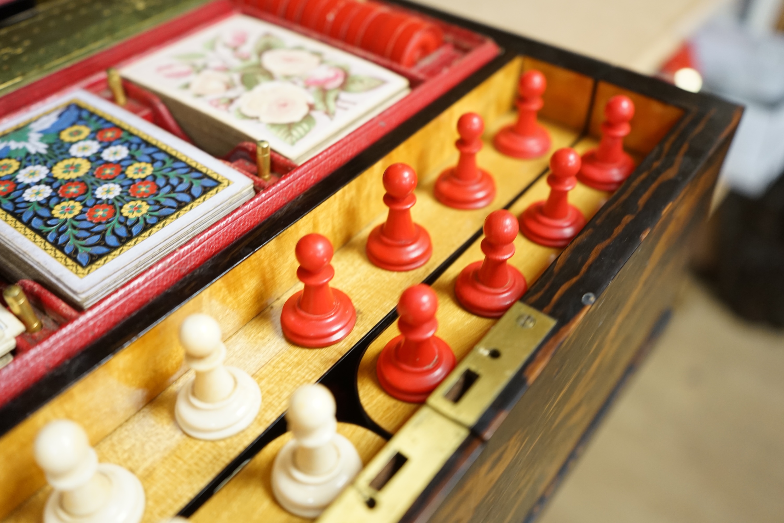 A Victorian coromandel games box with accessories, ivory chess pieces and counters, box 36cm wide x 19cm high. Condition - red interior leather worn and torn in places and box scratched, minor losses to chess pieces. CIT